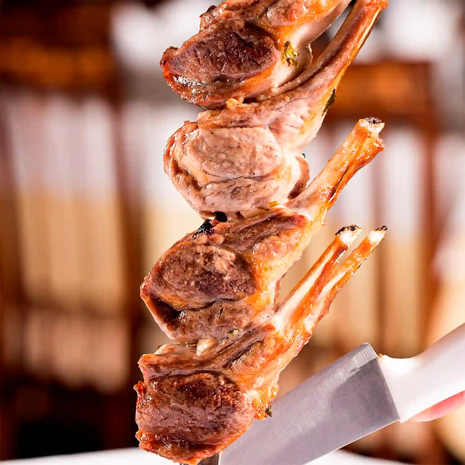 Fotografia gastronômica da Jadineira: costelas grelhadas espetadas, em close sobre fundo escuro