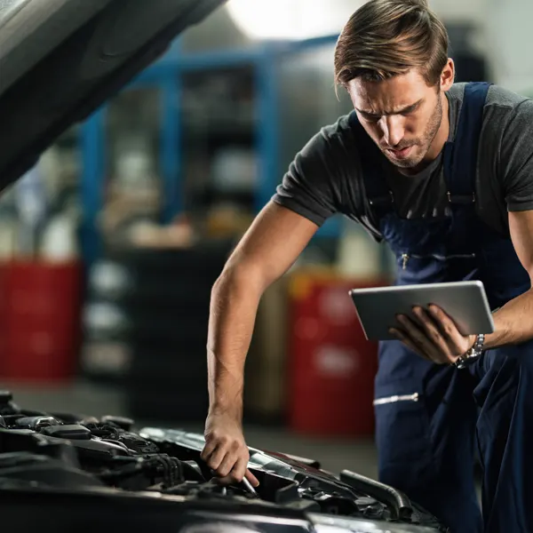 Mecânico de oficina fazendo diagnóstico do motor com tablet